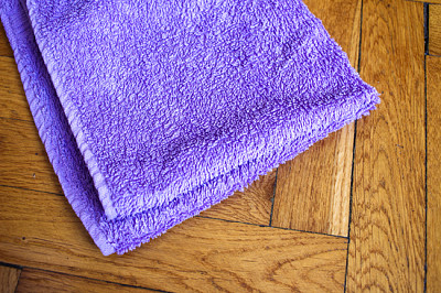 Färgglad böjd handduk på träbakgrund: lila c