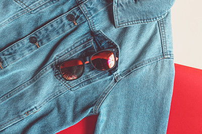 Solglasögon i jeansjacka på en färgad b