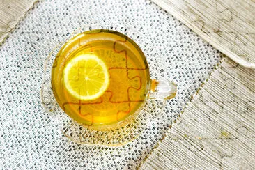 Above view of a glass of tea with lemon slice on a jigsaw puzzle