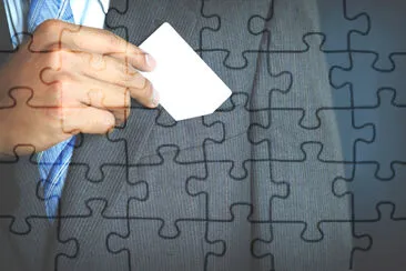 Young businessman holding white business card and  jigsaw puzzle