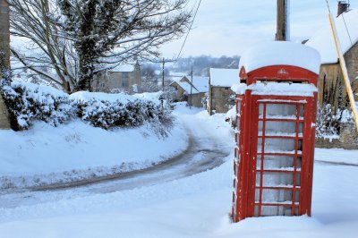 old red phone box in snow