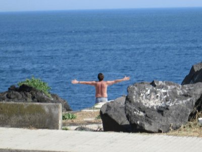 Un joven saluda el mar con sus brazos abiertos